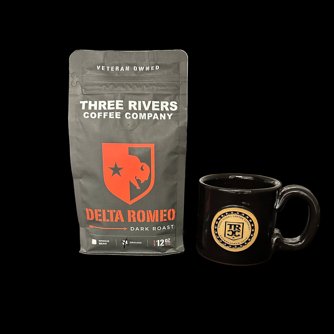 Three Rivers Coffee Company Delta Romeo Dark Roast 12 oz bag with a branded black mug, displayed in a veteran-owned coffee roastery.